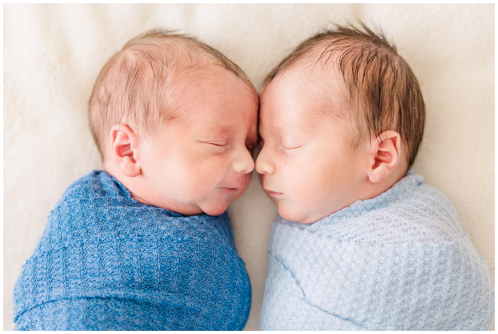 Sleeping newborn twin boys nose to nose