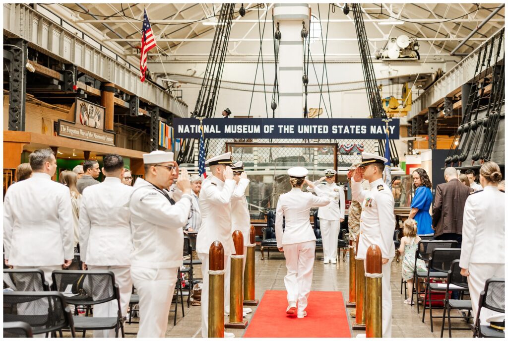 Service members saluting at Navy retirement ceremony