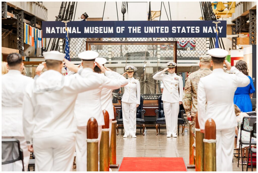 Service members saluting at Navy retirement ceremony