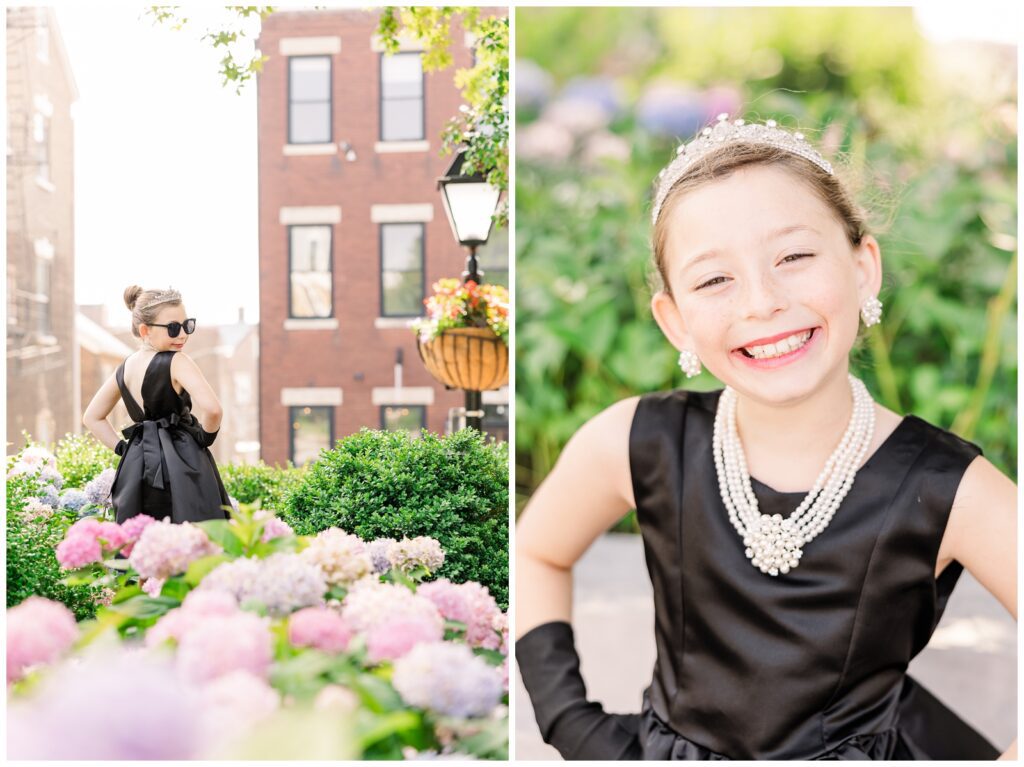 Little girl wearing pearls and a black dress standing near flowers