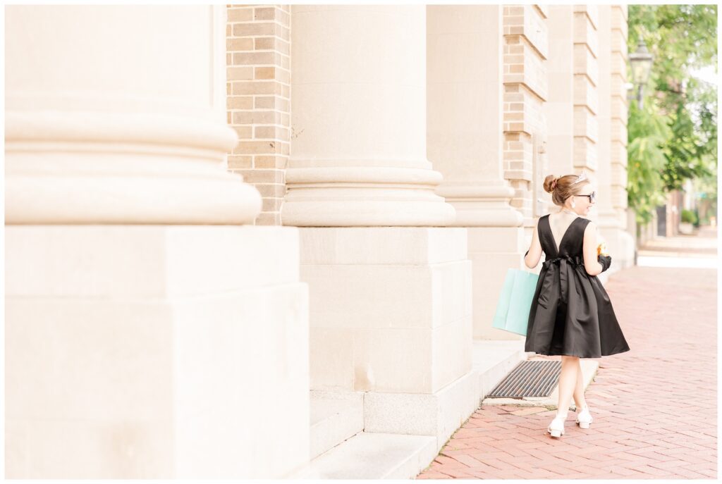 Girl in a black dress walking away with a Tiffany's bag