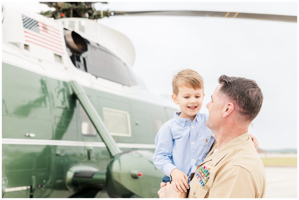 Dad holding son in front of a helicopter