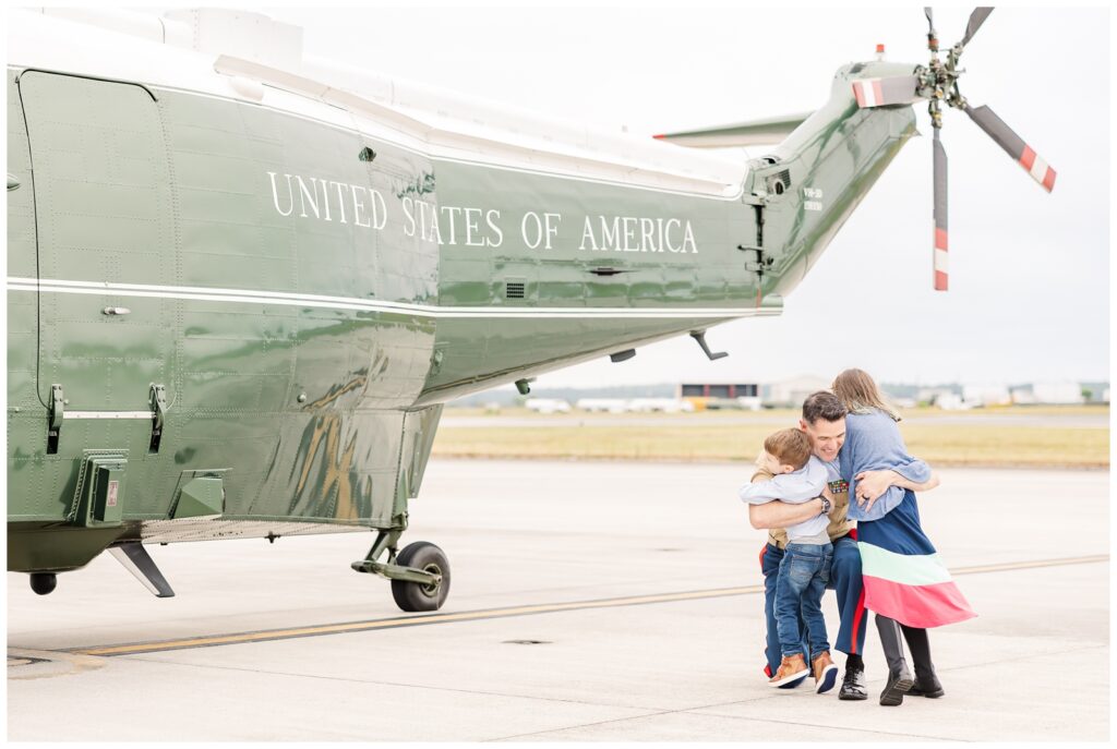 Dad hugging kids in front of Marine One aircraft