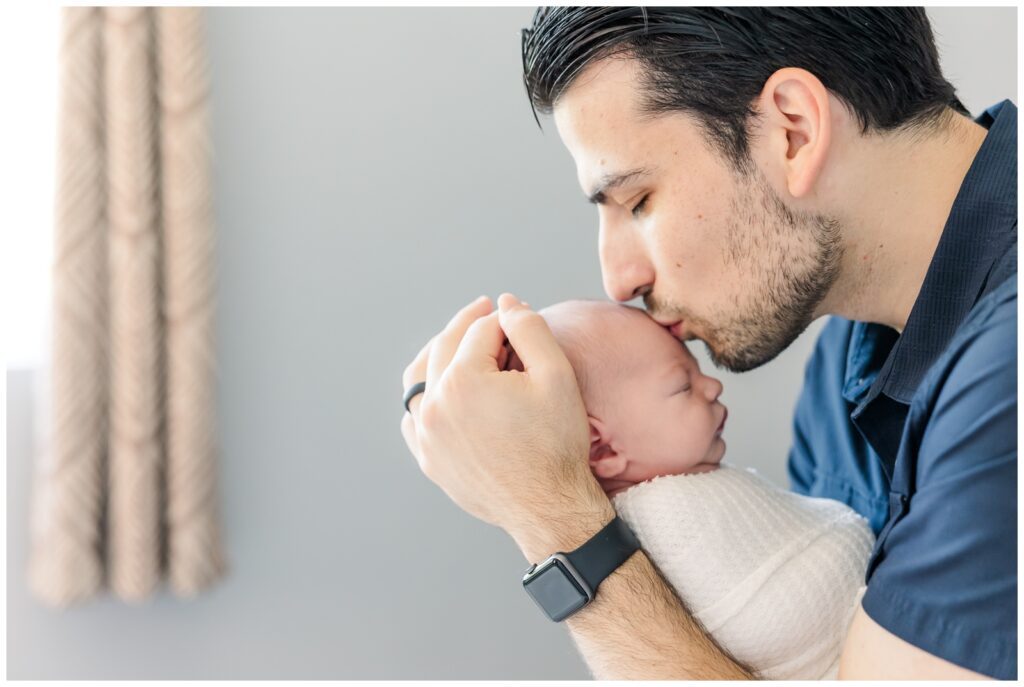 Dad kissing baby's forehead at their DC newborn photography session