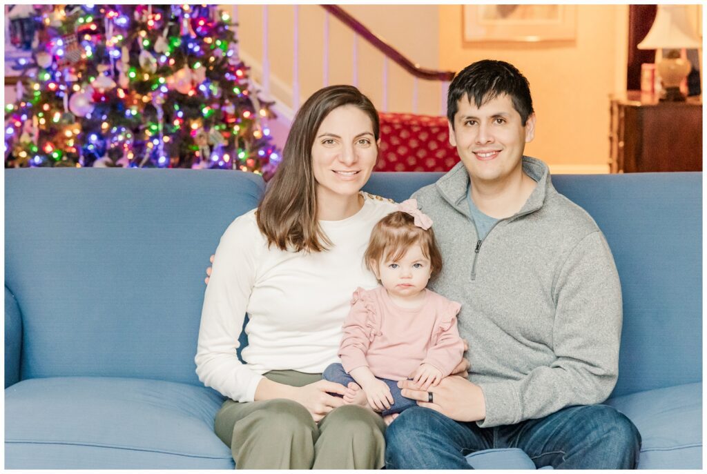 Family of three sitting in front of the Christmas tree