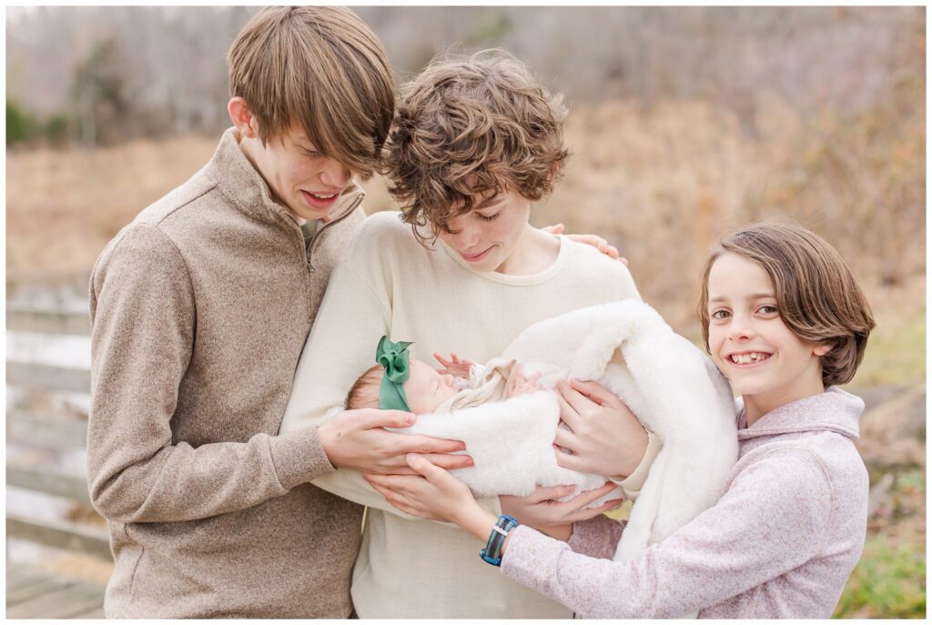 Big boy cousins holding their new baby girl cousin during NOVA extended family photos