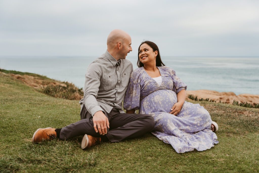Couple sitting and looking at each other at Law Street Beach in Marisa Glaser Creative's San Diego, CA photography spotlight