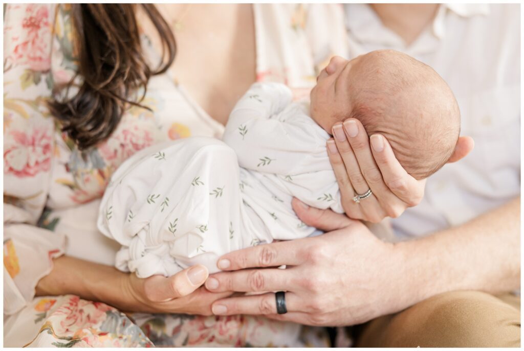 Closeup of parents' hands holding newborn baby