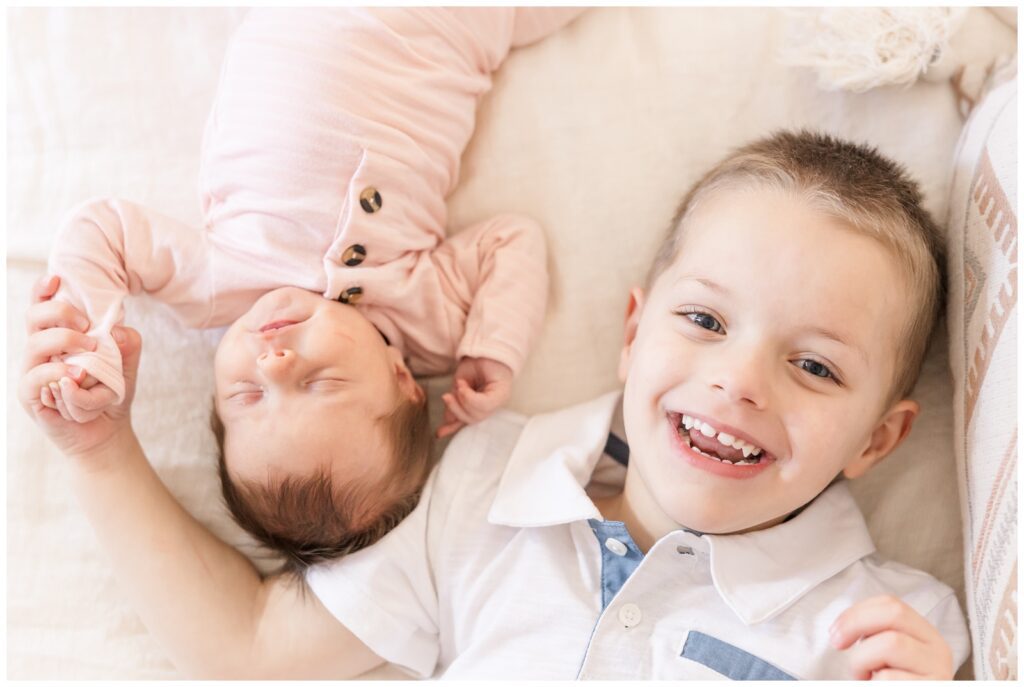 Smiling big brother with his sleepy baby sister, captured by Erin Thompson, Virginia newborn photographer