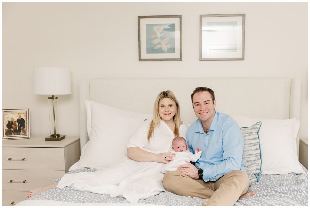 Parents and their new baby girl sitting on a bed for Arlington newborn photos
