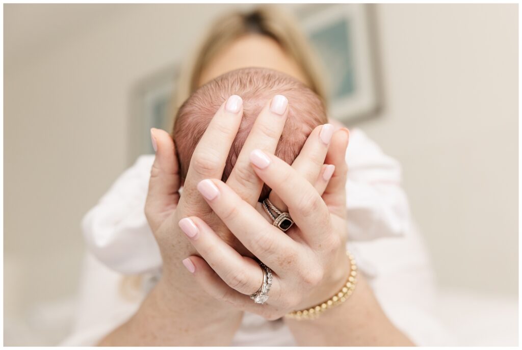 Closeup of mom's hands holding baby's head