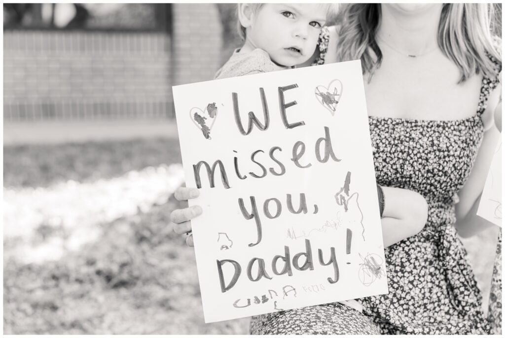 Little boy holding a "We missed you, Daddy!" sign at his Air Force deployment homecoming