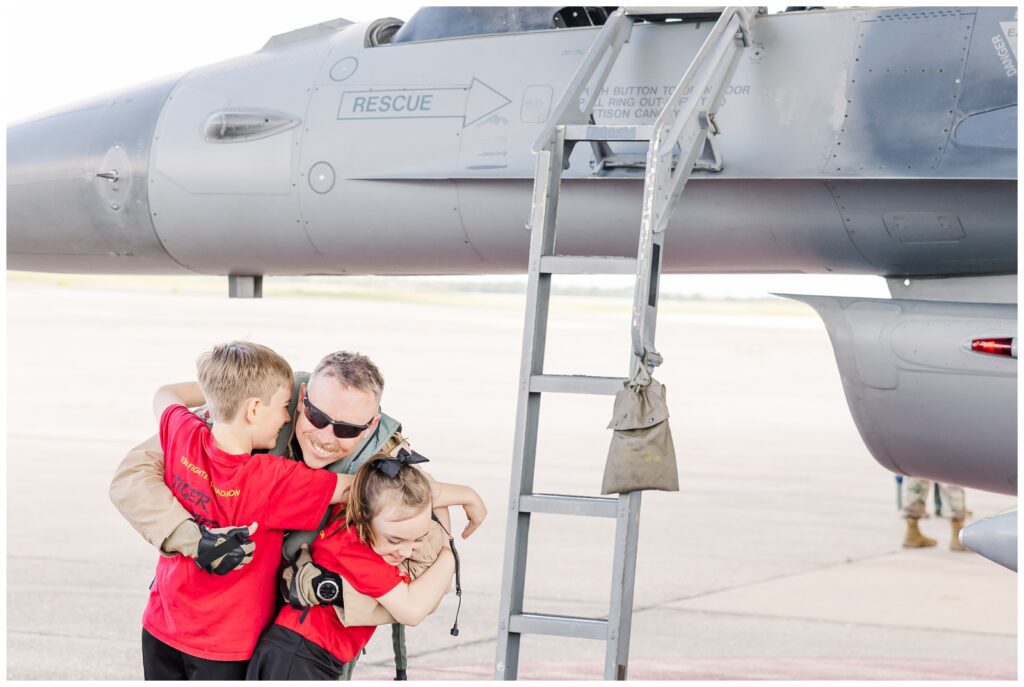 Dad hugging his kids in front of a jet