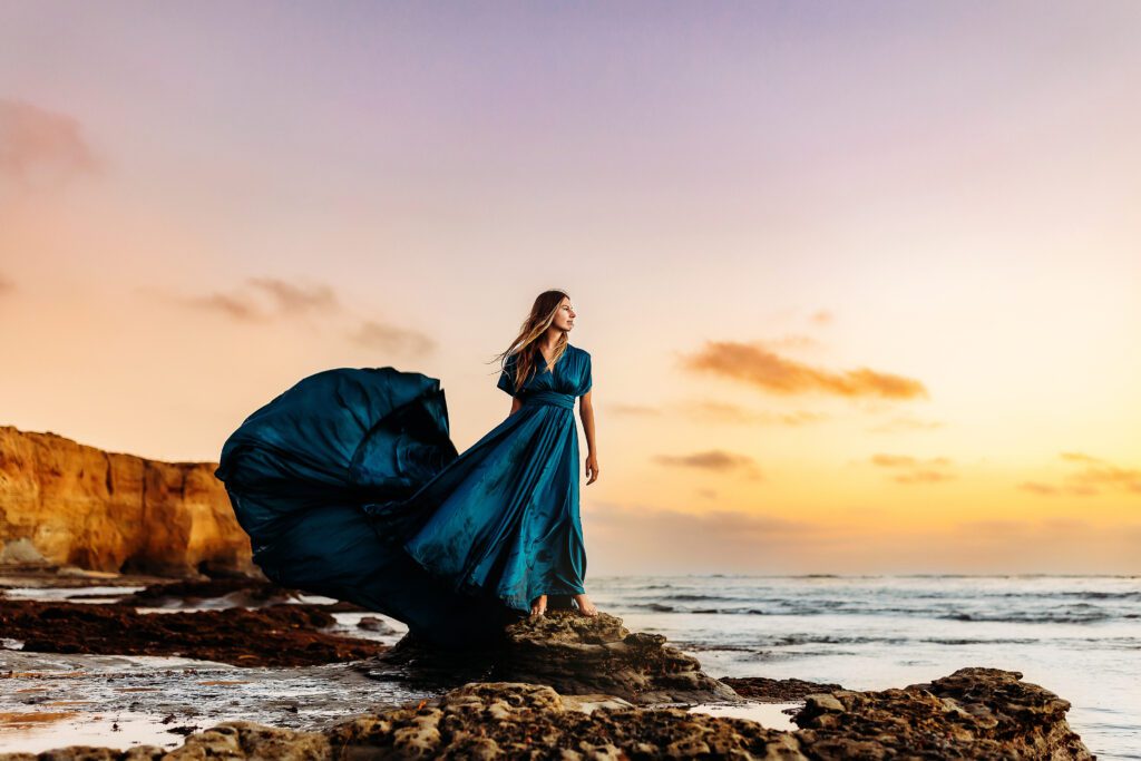 Woman in a gorgeous blue dress standing at Sunset Cliffs in Christa Paustenbaugh Photography's Oceanside, CA Photography Spotlight