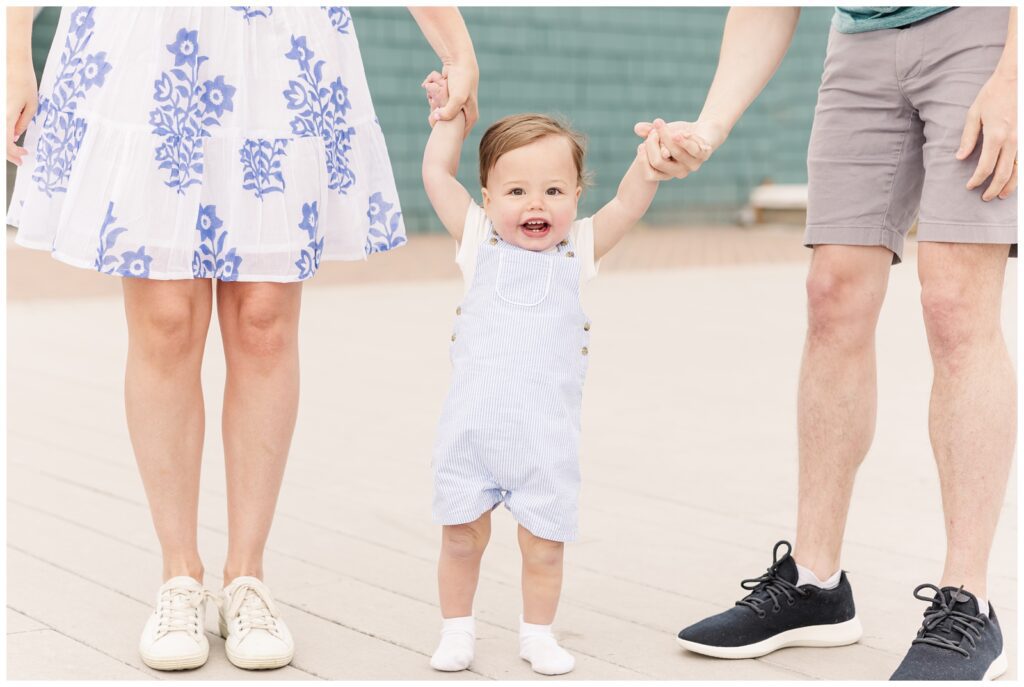 Toddler boy holding his parents hands and walking