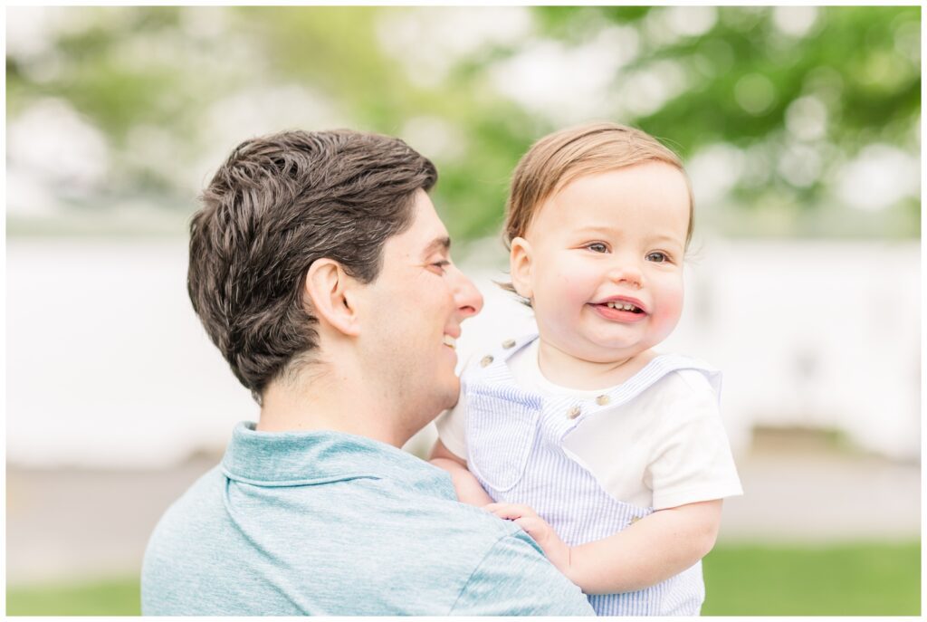 Baby peeking over his dad's shoulder during spring family photos