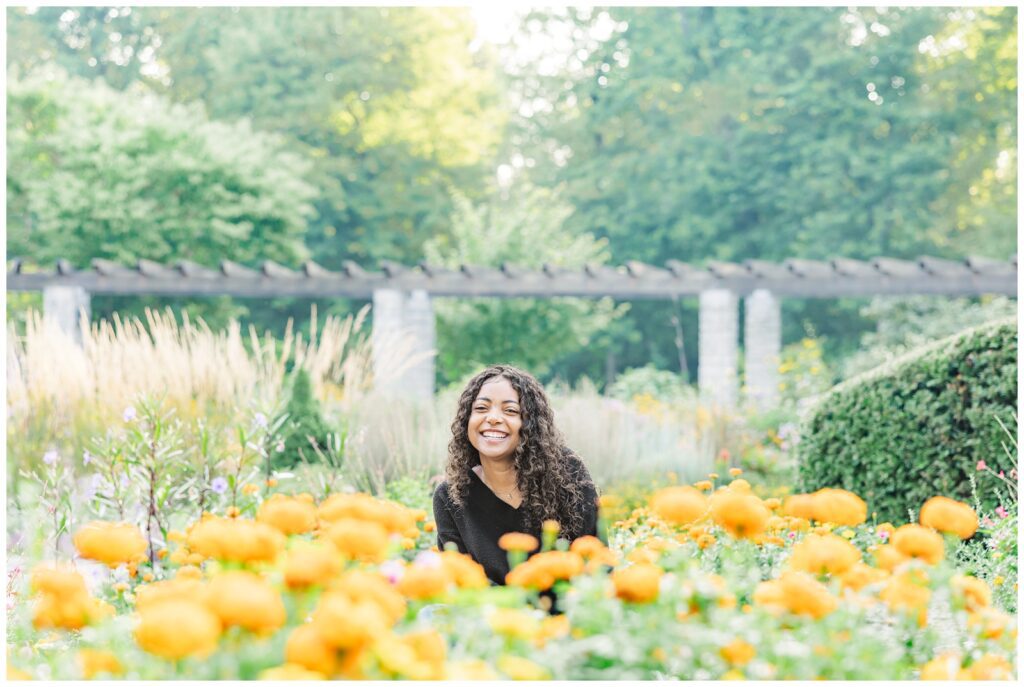Senior girl smiling among flowers and greenery in Erin Thompson Photography's Dayton, OH photography spotlight