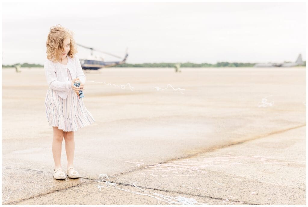 Little girl spraying silly string on the flight line by a Colorado Springs fini flight photographer