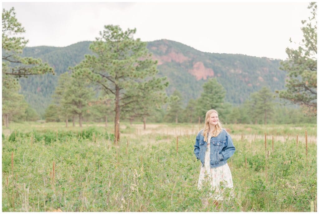 Senior girl standing in a field in front of Mt. Herman getting her Colorado Springs senior photos